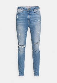 Jeans ajustados de color azul claro con detalles desgastados, que presentan áreas rasgadas en las rodillas, cierre de cremallera y diseño clásico de cinco bolsillos.