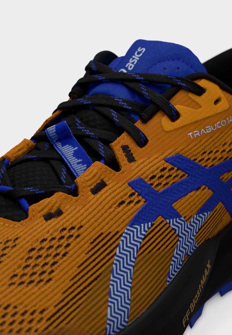 Les chaussures Asics Trabuco 14 présentent une tige texturée orange et bleue, des lacets noirs, des accents en motif zigzag et une semelle noire durable.