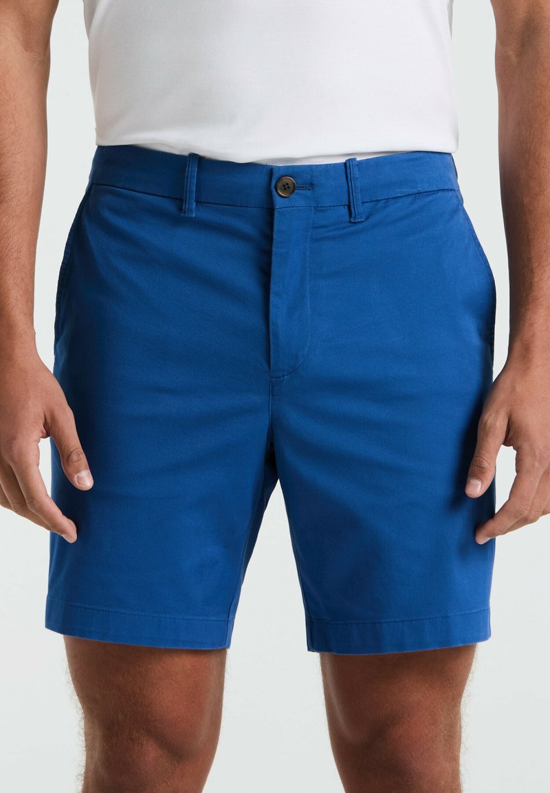 Blaue Shorts aus leichtem Material mit einem vorderen Reißverschluss und Knopfverschluss, zwei seitlichen Taschen und einem geraden Schnitt am Saum.