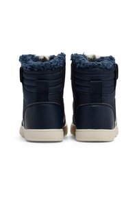 Granatowe sneakersy typu high-top z teksturowanej skórzanej powierzchni, pluszowym niebieskim futerkiem na kołnierzu oraz białą gumową podeszwą. Zapięcie na rzep.