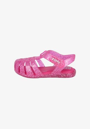 Sandalias brillantes rosas con un diseño abierto, que presentan cortes laterales y una correa ajustable. Hechas de un material plástico flexible.