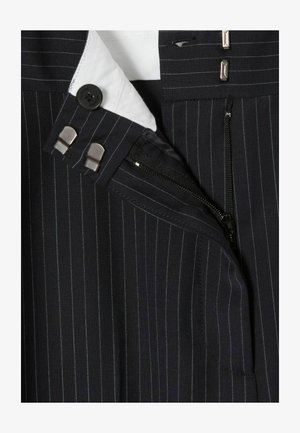 Tela a rayas marinas con bolsillo con cremallera, cierre de botones y forro de cuello blanco. El diseño está confeccionado con detalles metálicos.