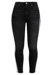 Jeans skinny negros hechos de denim, con franjas laterales blancas que llevan estampados de logotipo. Diseño de cintura alta, textura suave y ajuste ceñido.