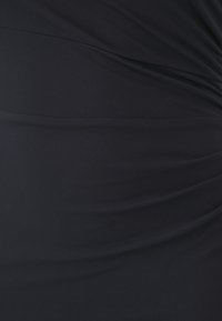 Black, stretchy fabric with a softly gathered texture, featuring subtle pleats that create a smooth, flowing appearance.