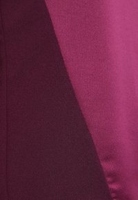 Tvåfärgad tyg i djup burgundy och livfull magenta, slät textur med en subtil lyster, med en diagonalt färgblockdesign.