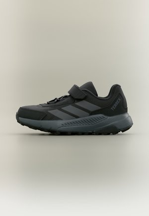 Zwarte en donkergrijze Adidas Terrex buitenschoen met klittenbandsluiting, drie zijstrepen en een gevoerde zool, zijaanzicht.
