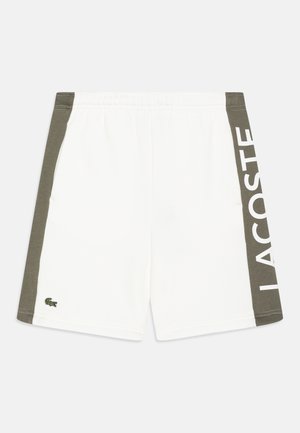 Hvide shorts med olivengrønne sidepaneler, elastisk linning, lille broderet krokodille-logo og stor "LACOSTE"-tekst på højre sidepanel.