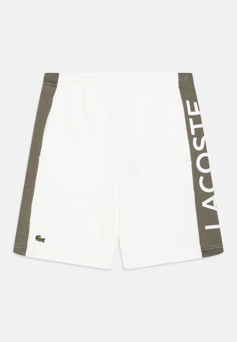 Short blanc avec panneaux latéraux vert olive, taille élastique, petit logo crocodile brodé et grand texte "LACOSTE" sur le panneau latéral droit.