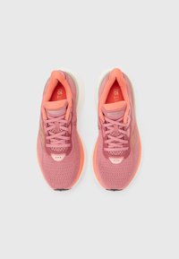 Ζευγάρι ροζ αθλητικά παπούτσια με ροδακινί λεπτομέρειες, διχτυωτά επάνω μέρη και κορδόνια, σε άποψη από πάνω πάνω σε ανοιχτό φόντο.