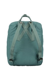Sac à dos en tissu vert avec des bretelles réglables, de forme rectangulaire et deux poignées supérieures. Présente deux boutons pour la fermeture et des coutures robustes.