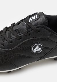 Zapato de fútbol negro con parte superior de cuero texturizado, punta redonda, diseño con cordones y detalle de logotipo blanco en el costado. Suela con tacos.