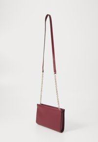 Burgunderfarget lær crossbody-veske med en jevn tekstur, som har en gullfarget kjede-reim og en stilren rektangulær form.