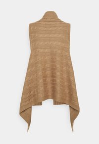 Beige stickad poncho med ett strukturerat kabelmönster, med öppen fram och en lätt asymmetrisk fåll. Mjuk material, inga knäppningar.