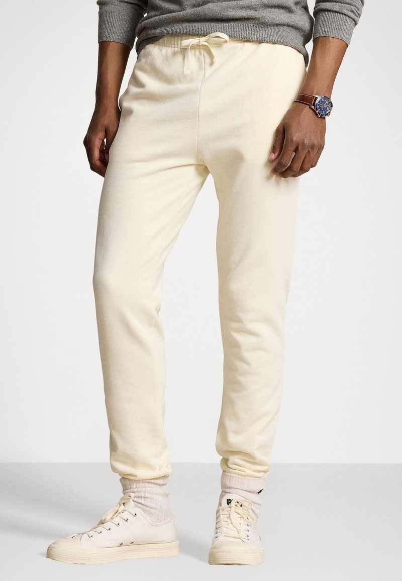 Krämfärgade sweatpants i mjukt tyg med elastisk midja och justerbar dragsko. Bärs med vita sneakers och ljusa strumpor.