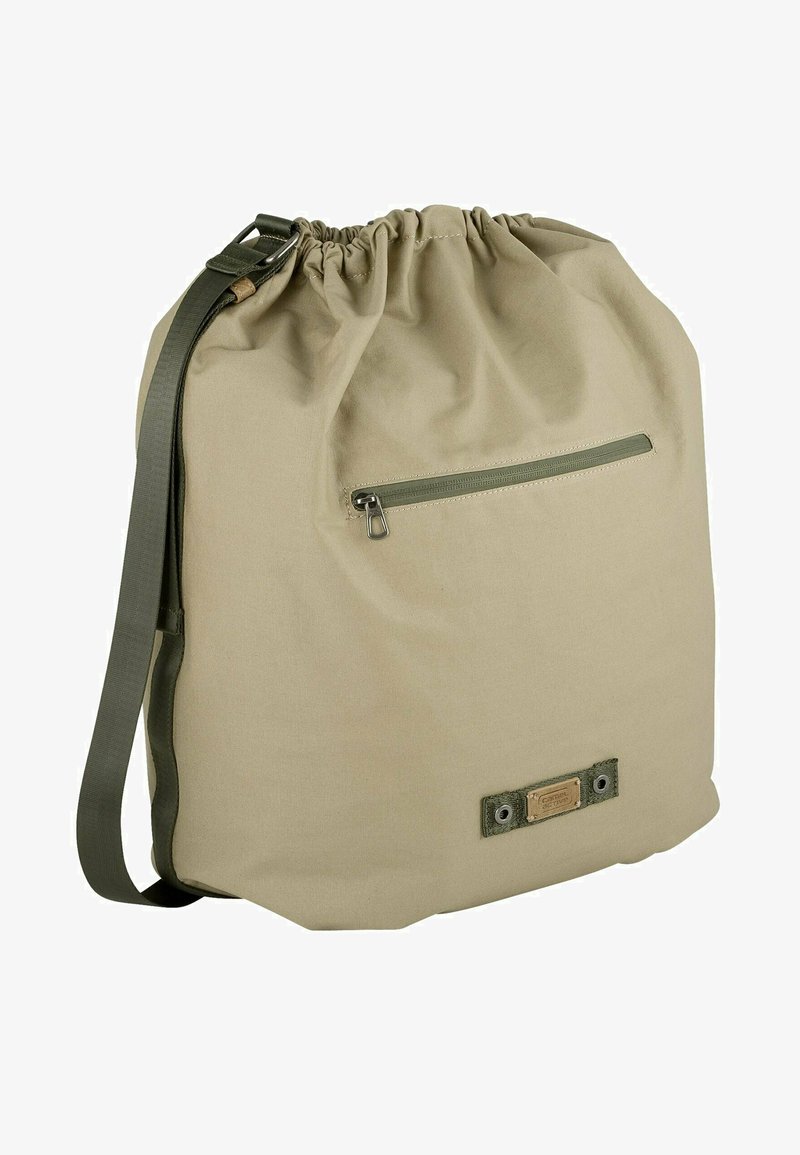 Beige lærredstaske med snoretræk i toppen, justerbar grøn strop og en lynlåslomme foran. Har et lille logopatch på bunden.