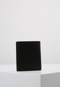 Portafoglio in pelle nera con una texture granulosa, forma rettangolare, bordi lisci e un piccolo logo in rilievo sulla parte frontale.