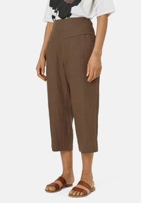Bruine linnen cropped broeken met een brede elastische tailleband en zijzakken, gecombineerd met bruine leren sandalen. Soepele textuur, ontspannen pasvorm.