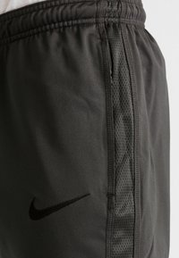 Pantalones cortos deportivos de Nike en tejido gris oscuro, con una textura suave y un panel de malla a lo largo del costado, además de un pequeño logo negro.
