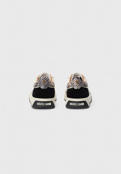 Par av låga sneakers med ormskinnsmönster, svart mocka häl, vit sula och "roberto cavalli"-logotyp på baksidan.