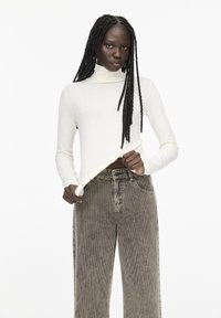 Tricou alb cu mânecă lungă și guler înalt, asociat cu pantaloni din catifea cu talie înaltă și croială largă, având un model în tonuri de gri estompat. Textură netedă în ansamblu.