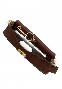 Pochette bracelet en daim marron avec garniture dorée, tenant un smartphone, un étui blanc pour écouteurs sans fil et une clé avec un porte-clés Coach doré.