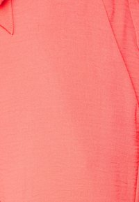 Koralltyg med en mjuk, texturerad yta. Bilden visar en närbild av veck och ett naturligt fall. Inga synliga mönster eller hårdvara.