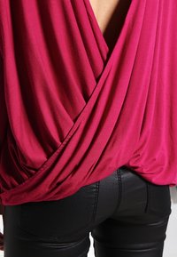 Fuchsia Wickeloberteil mit drapierter Stoff, ausgestattet mit tiefem V-Ausschnitt hinten und glatter Textur, kombiniert mit enganliegenden schwarzen, glänzenden Leggings.