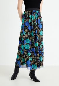 Maxikjol med svart bas som har livfulla blå och teal blommönster. Elastisk midja, lättviktig tyg och svallande silhuett.