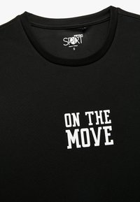 Zwart sport T-shirt met korte mouwen, gestructureerde stof, ronde halslijn, met de zin "ON THE MOVE" in dikke witte letters.