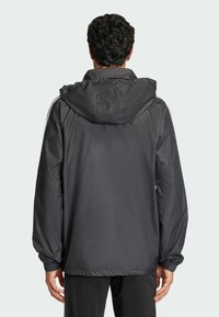 Ανδρικό γκρι αδιάβροχο μπουφάν με κουκούλα, ελαστικές μανσέτες και ρυθμιζόμενο στρίφωμα, με απαλή υφή και μινιμαλιστικό σχέδιο.