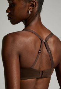 Bruine bh met verstelbare bandjes. Soepele stoftextuur, met een haak-en-oogsluiting en metalen hardware op de bandjes.