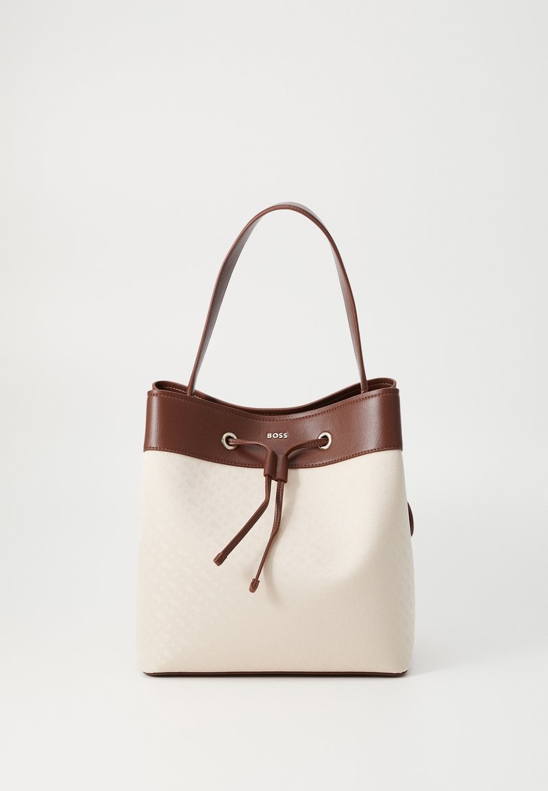 Torba typu bucket w kremowej tkaninie z brązowymi skórzanymi wykończeniami, z zaciąganym zamknięciem i srebrnymi okuciami. Charakterystyczne, wyraźne logo marki.