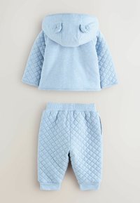 Felpa trapuntata azzurro chiaro con dettagli a orecchie di orso e pantaloni coordinati. Tessuto morbido, maniche lunghe e vita elastica.
