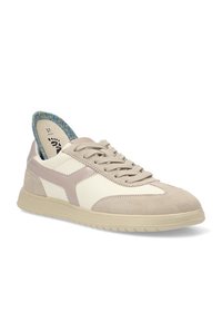 Zapato con puntera de ante beige, laterales de cuero crema y suela de goma beige. Presenta un collar acolchado multicolor y un sistema de cordones en la parte delantera.
