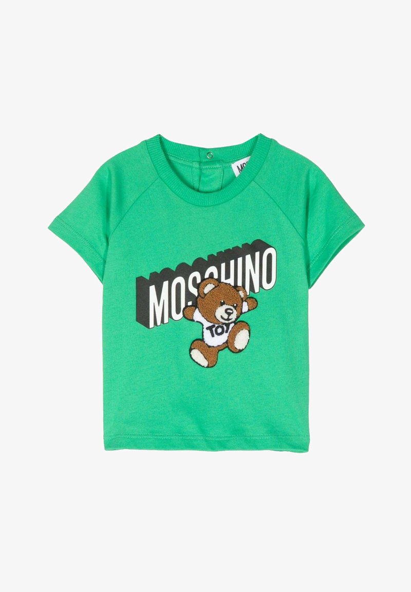 T-shirt in cotone verde con un blocco nero e testo bianco "MOSCHINO" e una grafica di un orsetto marrone che tiene una maglietta bianca con la scritta "TOY."