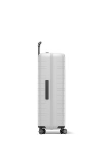 Hard-shell suitcase, matte white finish, vertical ribbed design, retractable handle, four black wheels, side handle for easy lifting.