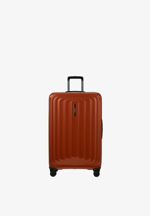 Hard-shell rust-orange suitcase with four black spinner wheels and a retractable black handle extended.