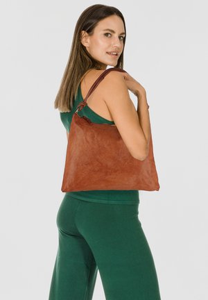 Borsa a spalla in pelle marrone con una texture morbida e un design rilassato. Presenta una tracolla unica ed è ambientata su uno sfondo chiaro.