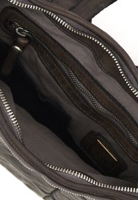 Interno di una borsa in pelle con molteplici tasche; tessuto marrone scuro, zip in argento e un motivo testurizzato; design pulito con scomparti funzionali.