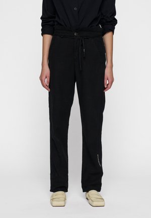 Pantaloni di lino neri con vita regolabile in cordino, taglio dritto, tasche laterali e dettagli testuali sottili sulla parte inferiore della gamba; texture liscia.