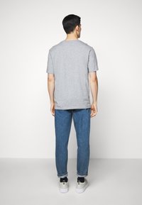 Camiseta gris de manga corta con un corte relajado, acompañada de jeans azules. La camiseta presenta un escote redondeado y una textura suave.