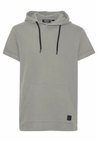 Camiseta de manga corta con capucha en tejido texturizado de color gris claro, con un bolsillo frontal y cordones negros en contraste. Parche rectangular del logo en el dobladillo.