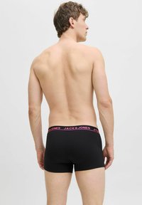 Schwarze Baumwollboxer mit pinkem Bund, auf dem das Logo "JACK & JONES" steht. Das Material ist glatt und hat eine taillierte Form.