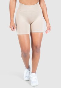 Beige hoge taille shorts gemaakt van rekbaar materiaal, met een gladde textuur en een aansluitend ontwerp, gecombineerd met witte sneakers.