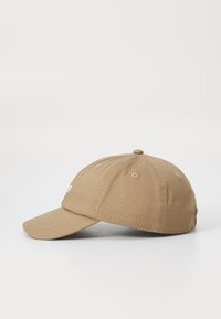 Khaki baseball cap med syet detaljer, buet skygge og ventilationshuller. Har et lille logo broderet foran.