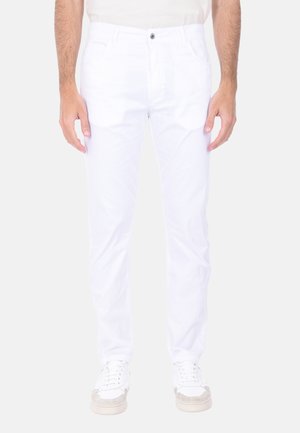 Pantaloni in denim bianco con vestibilità slim, dotati di tasche anteriori, chiusura a bottone e cerniera, e una texture liscia. Indossati con sneaker bianche.