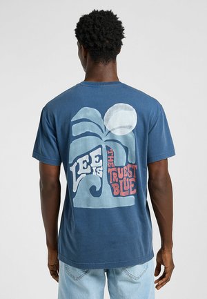 Marineblå bomulds t-shirt med et stort grafik på bagsiden, der viser et blad, sol og tekst. Designet inkluderer lyseblå og røde accenter.