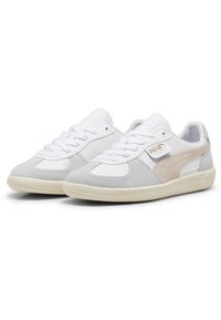 Białe i szare sneakersy z mieszanką zamszu i skóry, teksturowaną podeszwą, sznurowanym designem oraz szczegółami logo na bocznej części.