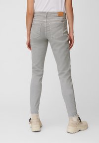 Šedé džíny skinny s zadními kapsami a béžovým koženým štítkem na pasu. Nosí se s béžovými platformovými botami.