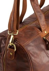 Braune Leder-Duffel-Tasche mit strukturiertem Finish. Sie verfügt über goldfarbene Hardware, zwei Tragegurte und einen auffälligen Reißverschluss.
